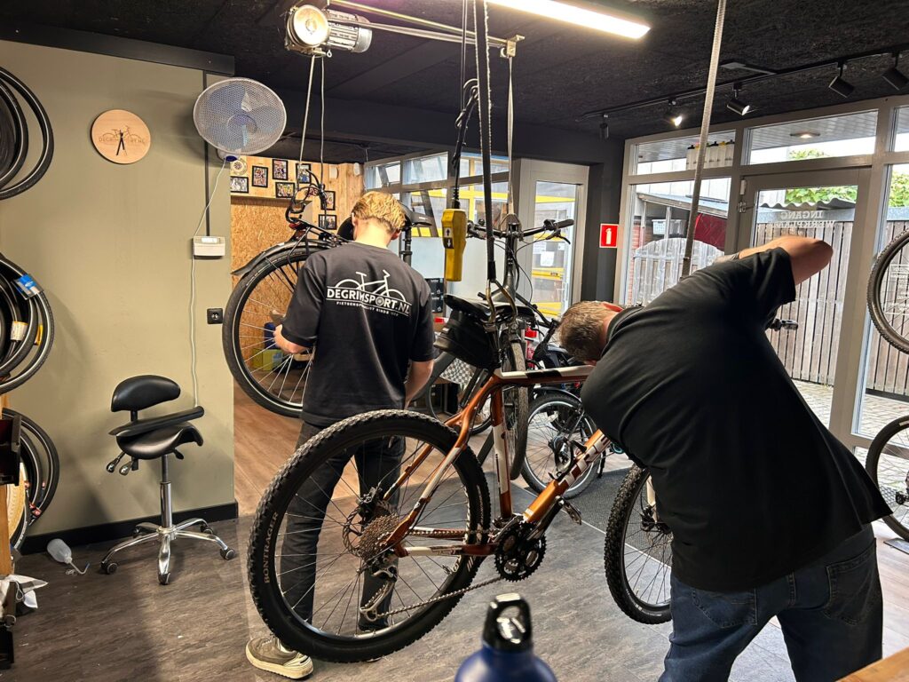 Monteur voert een fietsreparatie uit in de werkplaats van De Grim Sport in Zoeterwoude